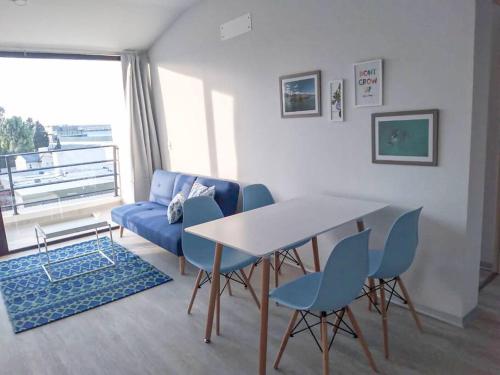 sala de estar con sofá azul, mesa y sillas en Luminoso departamento a una cuadra del mar Puerto Madryn en Puerto Madryn