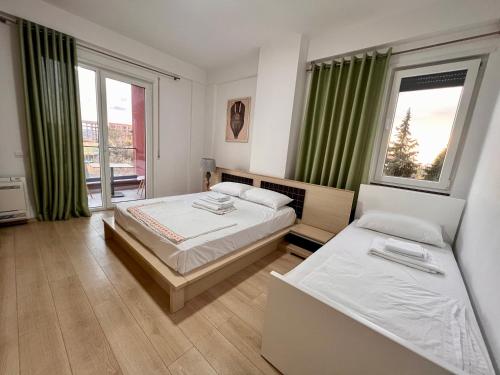 a bedroom with two beds and a large window at Kino Apartment in Tirana