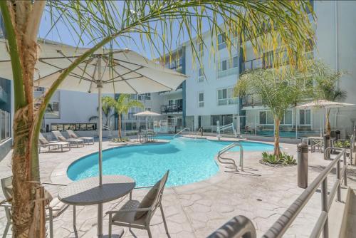a swimming pool with chairs and a table and an umbrella at Lux Oasis in West Hollywood, Free Parking & Swimming pool in Los Angeles