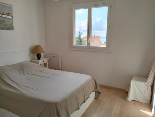 a white bedroom with a bed and a window at Charmant F3 lumineux proche plage et vue mer à Carqueiranne in Carqueiranne