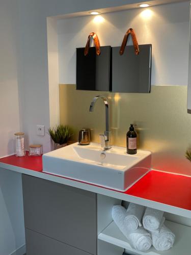 ein Badezimmer mit einem Waschbecken und einer roten Theke in der Unterkunft Appartement climatisé avec balcon et parking privé in Toulouse