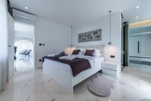 a white bedroom with a large bed and a mirror at Vortex apartments, Opatija Riviera in Matulji