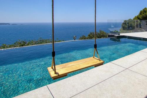- une balançoire dans une piscine avec l'océan en arrière-plan dans l'établissement VILLA L'OISEAU BLEU 220m2 VUE MER 180, GIENS & Porquerolles - Studio, à Carqueiranne