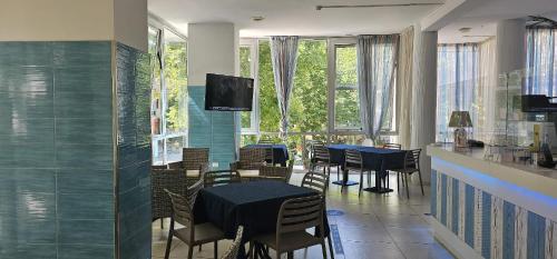 un comedor con mesas y sillas azules y ventanas en Hotel Napoleon, en Cesenatico