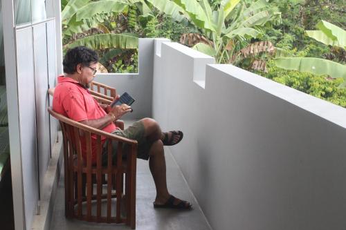 a man sitting on a bench reading a book at Forest Tree Top Holiday Resort in Buttala