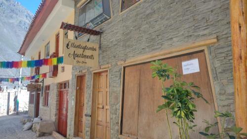 a stone building with wooden doors and flags on it at hostal ollantaytambo apartments in Ollantaytambo