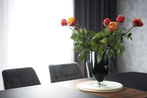 a vase with roses in it sitting on a table at Koala rest house in Druskininkai