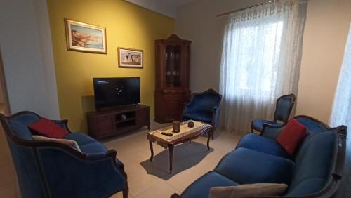 uma sala de estar com cadeiras azuis e uma mesa e uma televisão em Agathi's House em Preveza