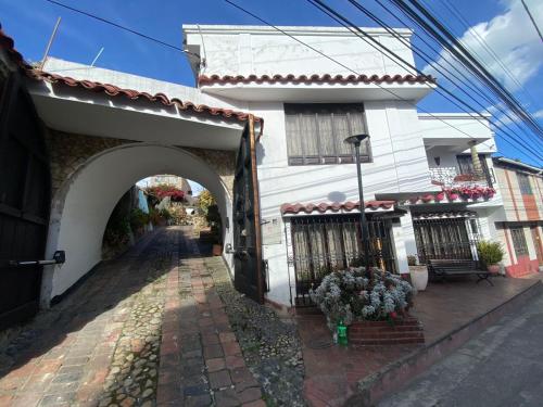 een wit gebouw met een boog naast een straat bij Home Mark Casa Boutique in Paipa