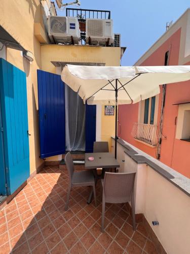 a table and chairs with an umbrella on a balcony at Casetta Giulia in Procida