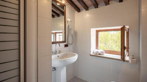 a white bathroom with a sink and a window at Agriturismo TerraMadre in Massa Marittima