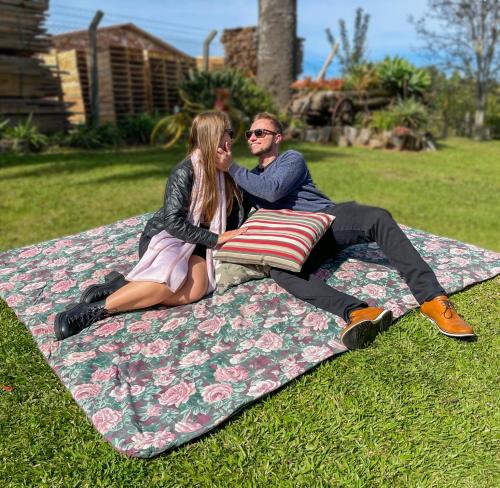 São Valentim do Sul的住宿－Cabana Aconchego do Recanto，坐在草上毯子上的男人和女人