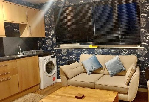 uma sala de estar com um sofá e uma máquina de lavar roupa em Lovely Centralised 1Bed Apt Near Town Centre & Beach - Free Wi-Fi & Parking em Fleetwood