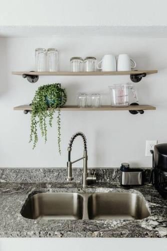 a kitchen sink with a faucet and a shelf with glasses at Westlake Apartment in Westlake
