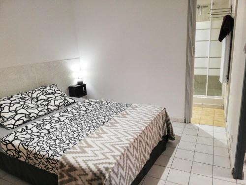une chambre avec un lit avec une couette noire et blanche dans l'établissement Charmant appartement en centre-ville médiéval, à Gigean