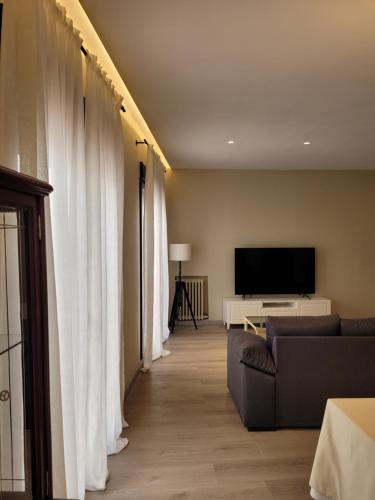 sala de estar con cortinas blancas y TV en La Casa Alandí con garaje privado, en Sagunto