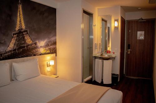 1 dormitorio con 1 cama con una foto de la torre Eiffel en Hotel Hi! Guadalupe, en Monterrey
