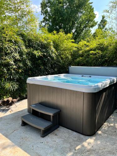un jacuzzi avec un banc devant des buissons dans l'établissement Maison périgourdine avec spa, à Saint-Cyprien