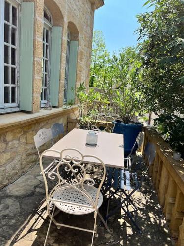 une table blanche et des chaises sur une terrasse dans l'établissement Maison périgourdine avec spa, à Saint-Cyprien