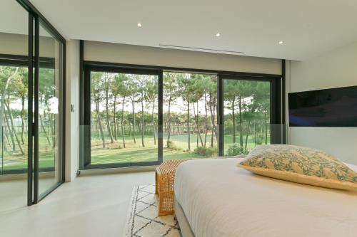 - une chambre avec un lit et de grandes baies vitrées dans l'établissement Villa Palm Green, aux Mathes