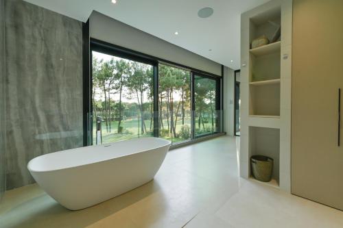 une baignoire dans une salle de bain avec une grande fenêtre dans l'établissement Villa Palm Green, aux Mathes