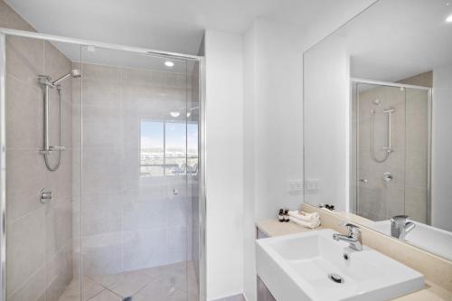 uma casa de banho branca com um chuveiro e um lavatório. em North Shore Oceanside Kawana em Kawana Waters