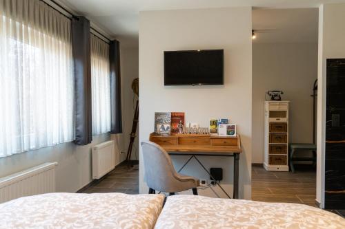 Schlafzimmer mit einem Bett, einem Schreibtisch und einem TV in der Unterkunft Maison Charlemagne Kelmis in La Calamine
