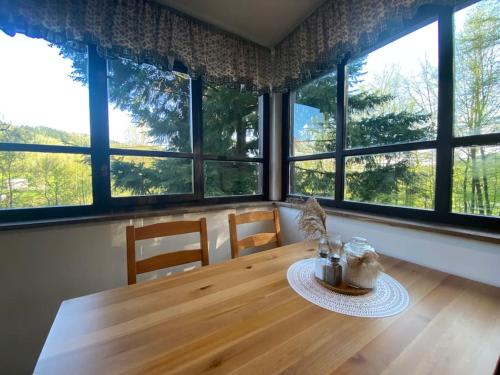 a dining room with a wooden table and windows at Chata pod pindulou in Rožnov pod Radhoštěm