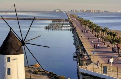 a pier with a windmill next to the water at Casa Bonita in San Pedro del Pinatar