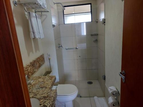 a small bathroom with a toilet and a shower at Plaza Suítes Natal in Natal