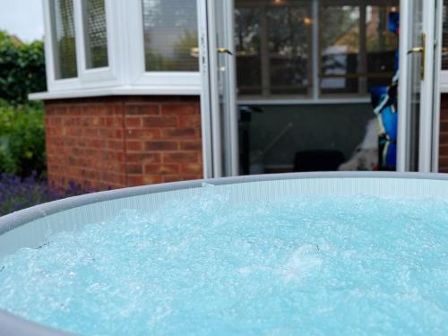 a hot tub filled with blue water in a yard at 4-bed Cotswold getaway with hot tub & gaming room in Churchdown