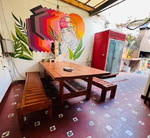 una mesa de madera y un banco junto a una pared con una pintura en Lacandona Hostel en Córdoba