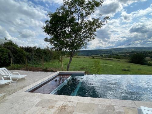 - une piscine avec deux chaises blanches et un arbre dans l'établissement bellevue, à Coux-et-Bigaroque