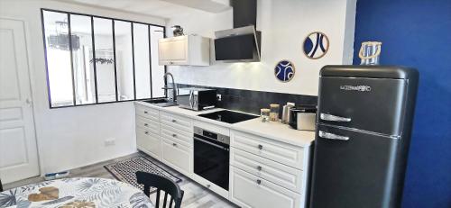 Il comprend une cuisine équipée d'un réfrigérateur noir et d'une table. dans l'établissement Bleu - Éden - appartement moderne en hypercentre, à Vichy