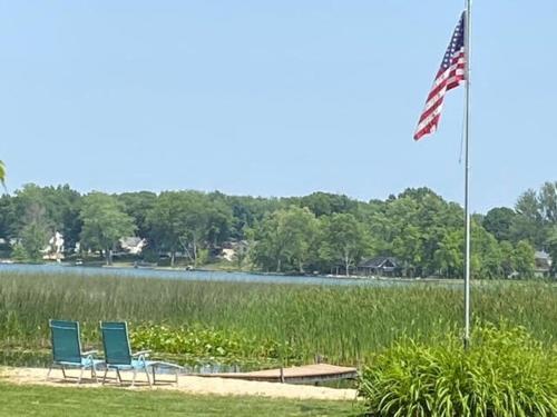 two chairs and an american flag in front of a lake at Amazing Lakefront Retreat On Long Lake! home in Portage