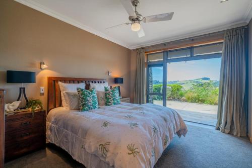 a bedroom with a bed and a large window at Luxury Country retreat in Cooks Beach