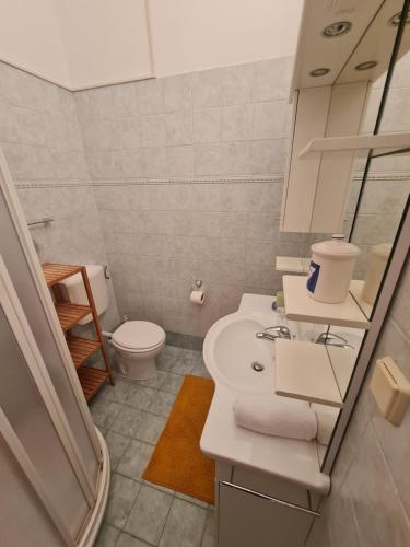 a bathroom with a white sink and a toilet at Apartments KUĆA SUNCE in Vodnjan