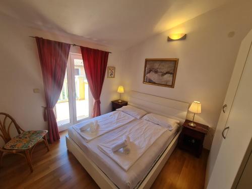 a bedroom with a white bed and a window at Apartments KUĆA SUNCE in Vodnjan