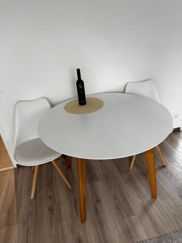 uma mesa branca e cadeiras com uma garrafa de vinho em City Apartment Nord em Salzburgo