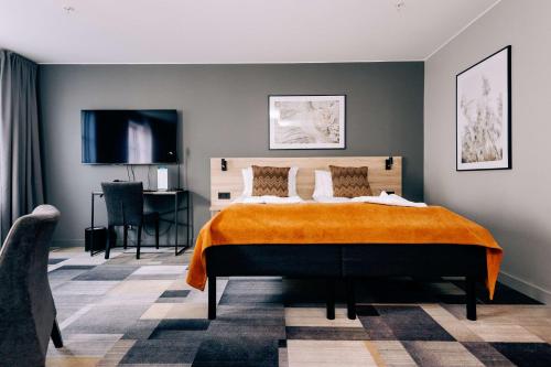 um quarto com uma cama com um cobertor laranja em Best Western Plus JA Hotel Karlskrona em Karlskrona