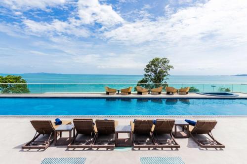 a pool with chairs and the ocean in the background at The Sanctuary Resort Pattaya, BW Signature Collection in Pattaya South