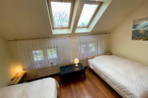 a attic bedroom with two beds and two windows at Apartament Kasztanowy Centrum in Zakopane