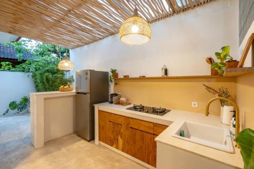una cocina con fregadero y refrigerador en Cozy Up Villa Sanur, en Sanur
