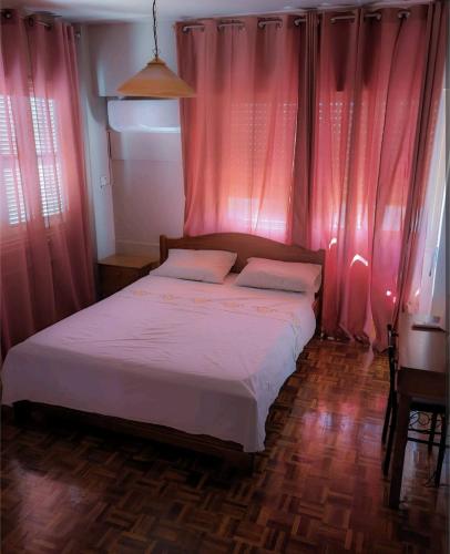 ein kleines Schlafzimmer mit rosa Vorhängen und einem Bett in der Unterkunft City center 3 bedroom apartment in Nikosia