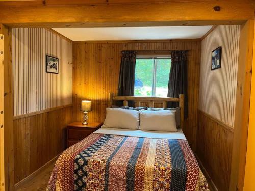 a bedroom with a bed and a window at Macwan's Lakefront Cottage in Calabogie