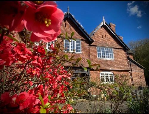 a brick house with red flowers in front of it at The Old Rectory with Valley View in Stockton on Teme