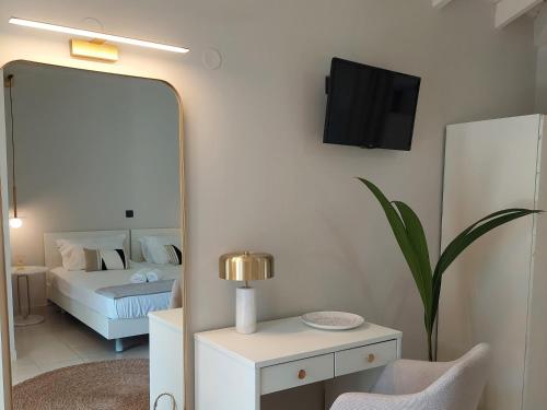 1 dormitorio con espejo, 1 cama y TV en Nikkos Apartments en Skála Kefalonias