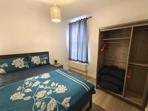 a bedroom with a bed with a blue comforter at Stylish flat in London with free parking in London