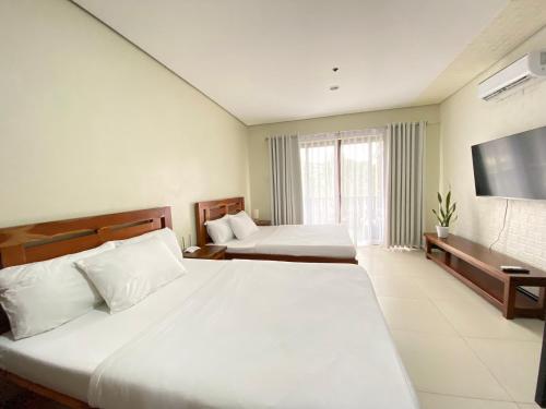 um quarto de hotel com duas camas e uma televisão de ecrã plano em Crosswinds Nature View Suite em Tagaytay