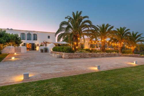 a house with a courtyard with palm trees and lights at Agroturismo Safragell Ibiza Suites & Spa in Sant Llorenç de Balafia